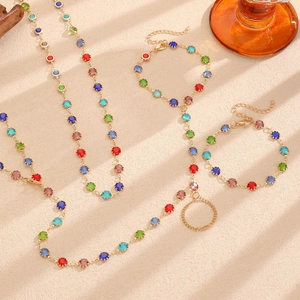 Detailed close-up of colorful gemstone necklace and bracelet set in gold finish