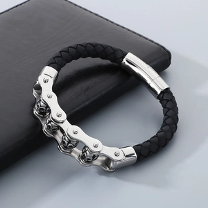 Detail of a punk leather bracelet with stainless steel skull elements on a black surface