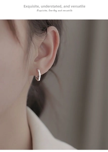 Close-up of minimalist silver hoop earring with hand-hammered texture on earlobe