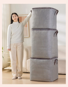 Close-up of three stacked houndstooth storage bags with brown handles in a home setting