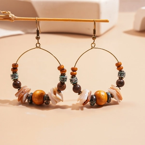 Close-up of bohemian hoop earrings with wood beads and shells on a branch