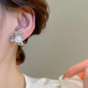 Detail of silver bow earrings with artificial pearls and zircons worn by a model