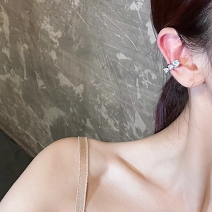 Primer plano de un ear cuff de corazón con circonitas brillantes en oreja sin agujero.