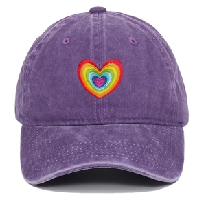 Detail of embroidered rainbow gradient heart on purple washed cotton baseball cap
