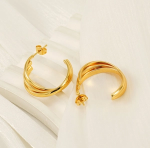 Detailed close-up of triple-layered interwoven 18K gold plated hoop earrings on white fabric