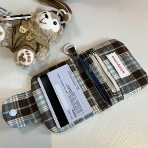 Detail of plaid card wallet showing credit card slots, zipper pocket and plush bear charm