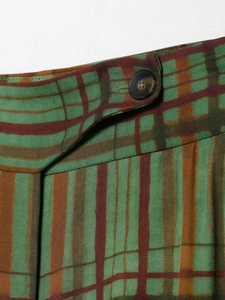 Detail der Karoblazer-Taille mit grün-braunem Karomuster und schwarzem Rundknopf