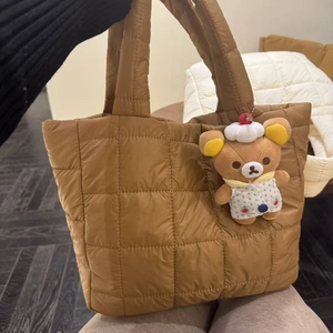 Detailed shot of brown quilted puffy handbag with a cute plush bear charm accessory