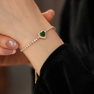 Detail of adjustable heart bracelet with emerald green stone and white zircon stones