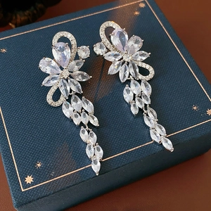 Detail of silver flower tassel earrings with sparkling zircons on a blue gift box