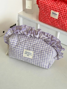 Close-up of purple plaid quilted makeup bag with ruffle trim and textured fabric detail