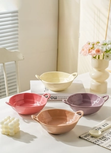 Detail of glossy ceramic bowls with dual handles in pastel pink, purple and cream yellow