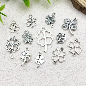 Detailed flat lay of eleven silver clover charms with varied hollow and solid patterns