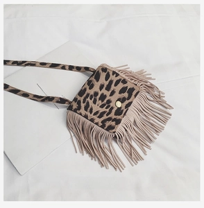 Flat lay of leopard print girl cross-body bag with tassels and gold button on white cloth