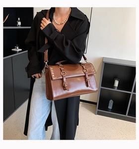 Detail of vintage brown shoulder bag showing metal rings, buckles and rivet accents