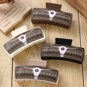 Detail of four PU leather hair claws featuring western bull skull patterns on wood background