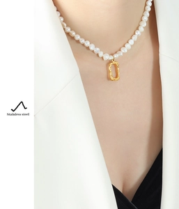 Detail of freshwater pearl necklace with gold textured pendant worn by a model