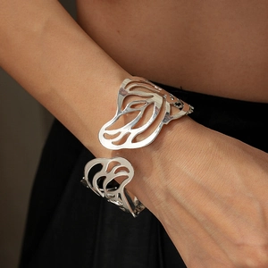 Macro shot of a silver butterfly cutout cuff bracelet worn on a woman's wrist