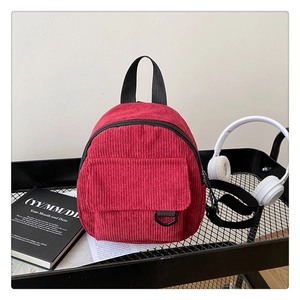Detailed close-up of mini red corduroy backpack with front flap pocket on a metal cart
