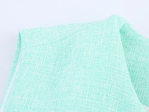 Gros plan sur la texture du tissu en tweed vert menthe pour un gilet à ceinture