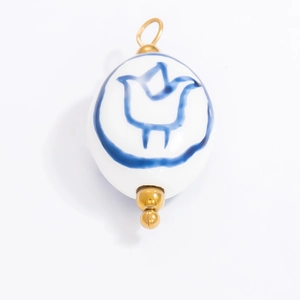 Blue and white ceramic bird pendant with gold metal hardware on a white background