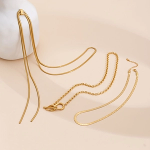 Three assorted gold-tone snake and curb chain necklaces displayed on a beige surface