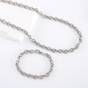 Set collana e bracciale a catena O spessa argentata su uno sfondo di pietra bianca