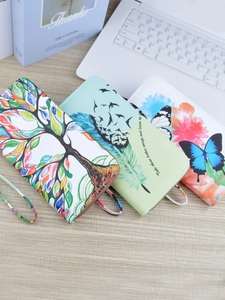 Long faux leather zipper wallets with tree and butterfly prints on wooden desk