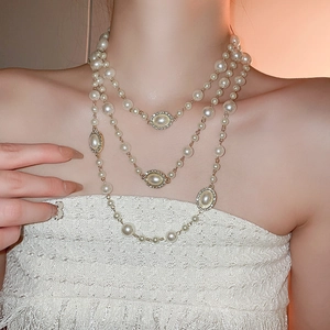 Detailed close-up of a three-layer pearl necklace with elegant rhinestone accents and gold finish