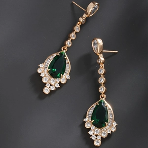 Detailed close-up of emerald green teardrop earrings with gold plating and crystals