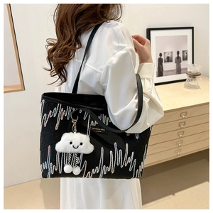 Close-up of black tote bag with colorful wave embroidery and a white cloud charm