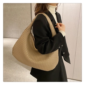 Beige woven leather tote bag shown on model with black blazer for professional look