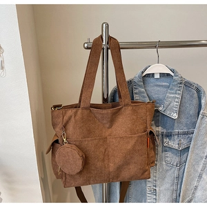 Detail of brown corduroy tote bag with small matching round pouch on a metal hanger