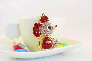 Detailed close-up of cute golden mouse keychain with sparkling red and clear rhinestones