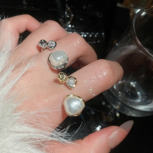 Detail of layered gold and silver rings with zircons and oversized pearls for women