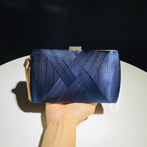 Detailed view of dark blue satin evening clutch bag with golden tassel and metallic lock