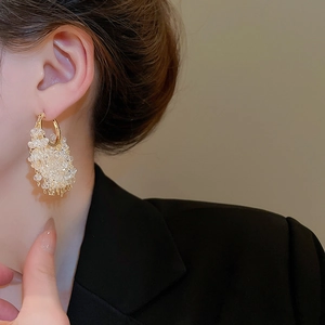 Close-up of 18k gold plated hoop earrings with cascading crystal fringe on a model