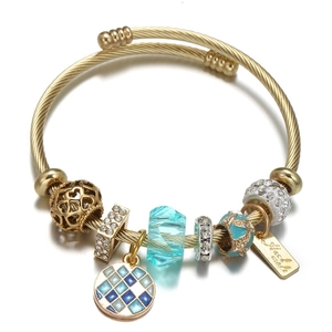 Primer plano de la pulsera multicapa de acero dorado con cuentas y dijes azules