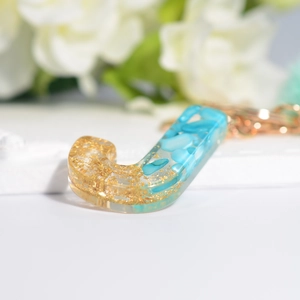 Detailed close-up of resin letter J keychain with turquoise stone and gold foil