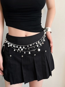 Detail of silver layered waist chain with pearls, shells and star charms on a model