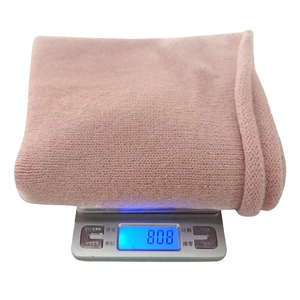 Detail showing the light pink chunky knit fabric texture and 80.8g weight on a scale