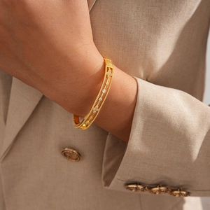 Detailed macro view of 18k gold plated bangle with zircon flower hollow design on wrist
