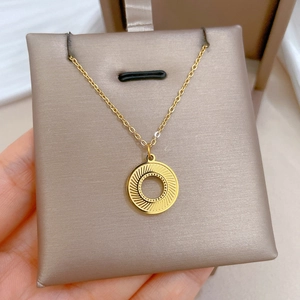 Macro shot of gold circular sunburst pendant on a beige jewelry display stand
