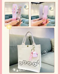 Close-up of cute pink cat cake roll silicone keychain attached to a canvas tote bag