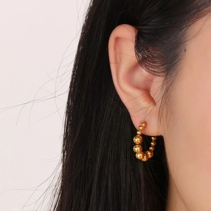 Orecchini a cerchio con perline in oro 18K mostrati di profilo su una modella reale