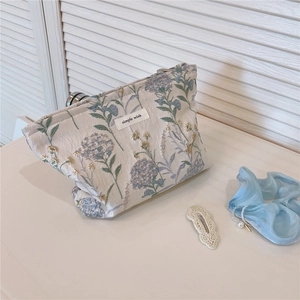 Detail of floral embroidery on a beige canvas makeup bag with a simple wish label