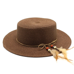 Close-up of woven straw sun hat featuring a delicate feather charm and beaded trim