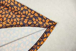 Detailed close-up of neat overlock stitching and autumn leaf print on a party dress