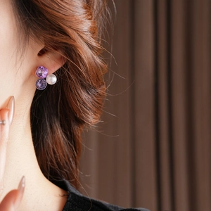 Detail shot of elegant triangle stud earring with purple rhinestones and white pearls
