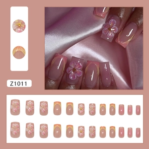 Faux ongles French dégradés roses avec pétales 3D et détails de perles dorées